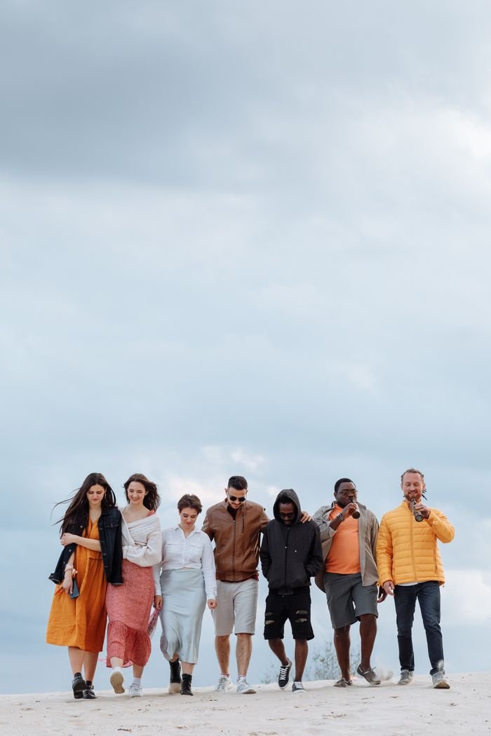 A diverse group of friends enjoying a walk under a cloudy sky, depicting unity and leisure.